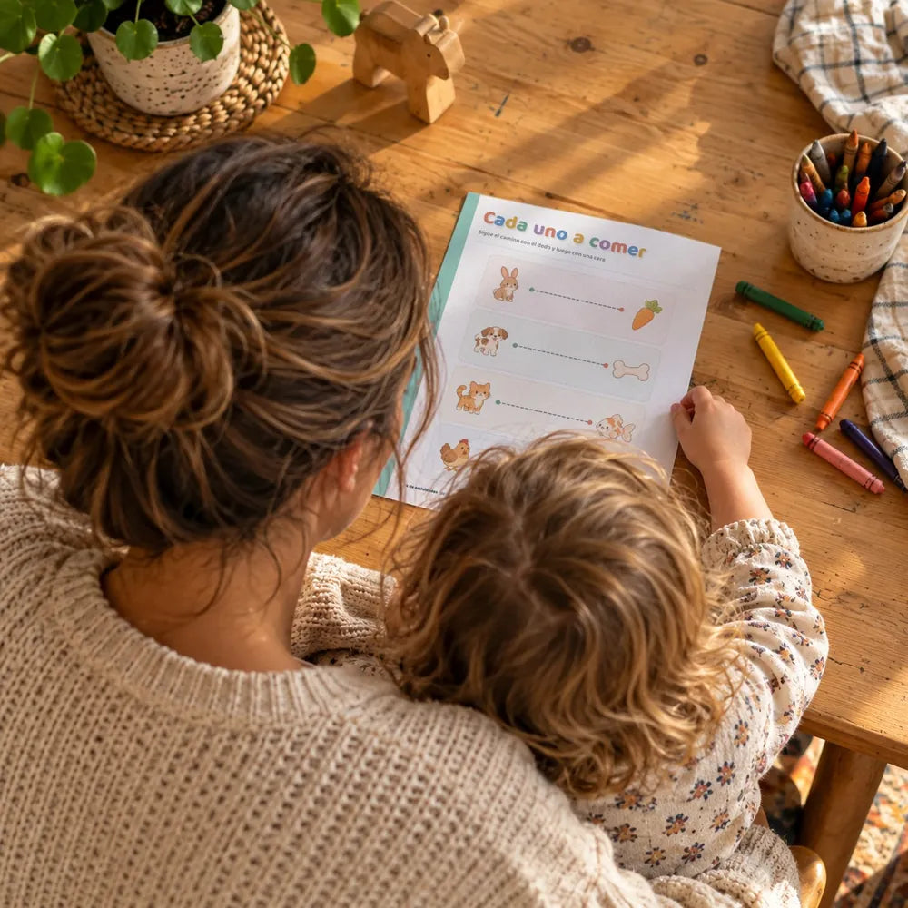 Una madre y su peque haciendo juntos una ficha de Pequeños Descubrimientos en la mesa
